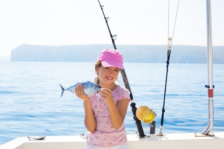 a little girl riding on the back of a boat
