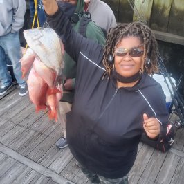 a group of people standing next to a man holding a fish