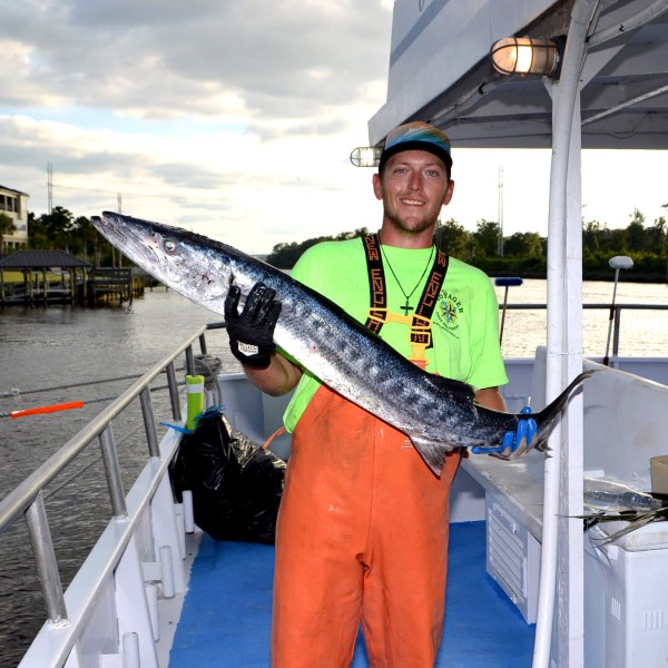a man holding a fish on a boat