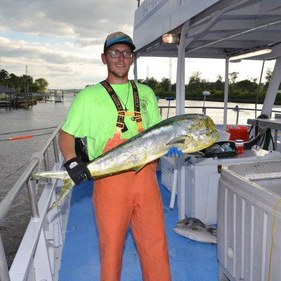 Adam Archuleta holding a fish on a boat posing for the camera