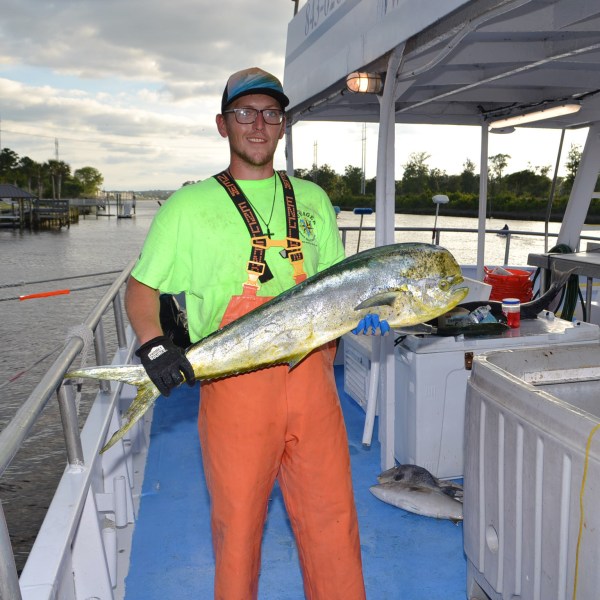 Adam Archuleta holding a fish on a boat posing for the camera
