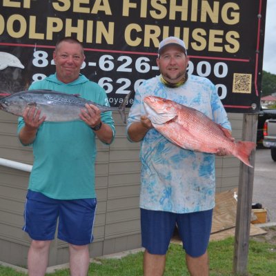a man holding a fish in front of a sign