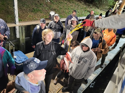 deep sea fishing in Myrtle Beach SC People gathered on a dock, one person displaying caught fish on a line.