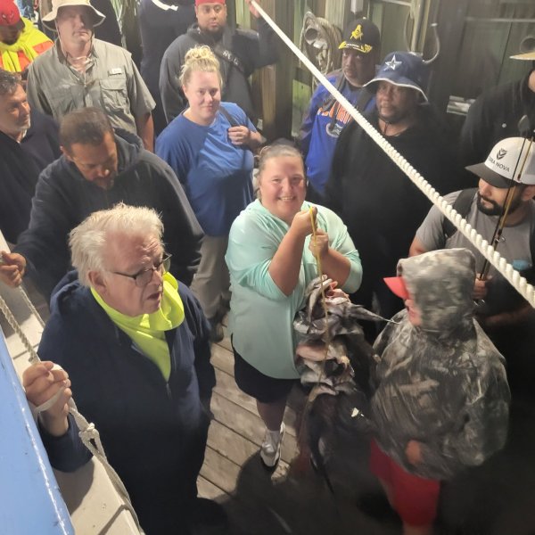 Group of people on a boat, one holding a fish.